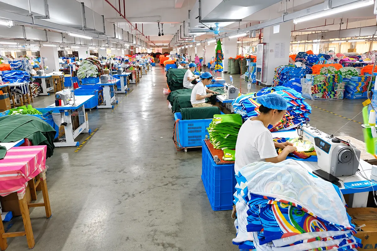 Workers sewing printed towels along a wide workshop aisle