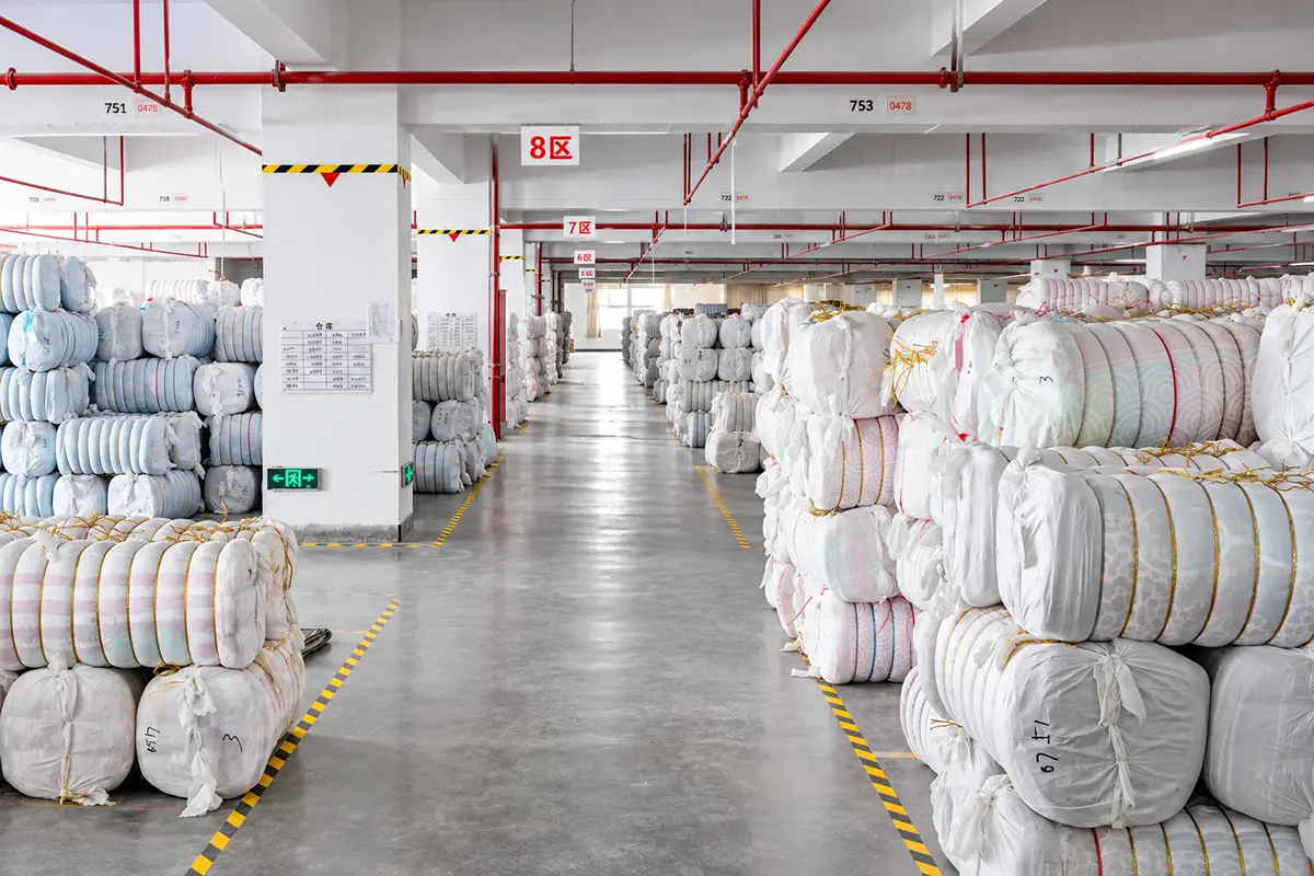 Wrapped fabric bundles stored beside marked warehouse aisles