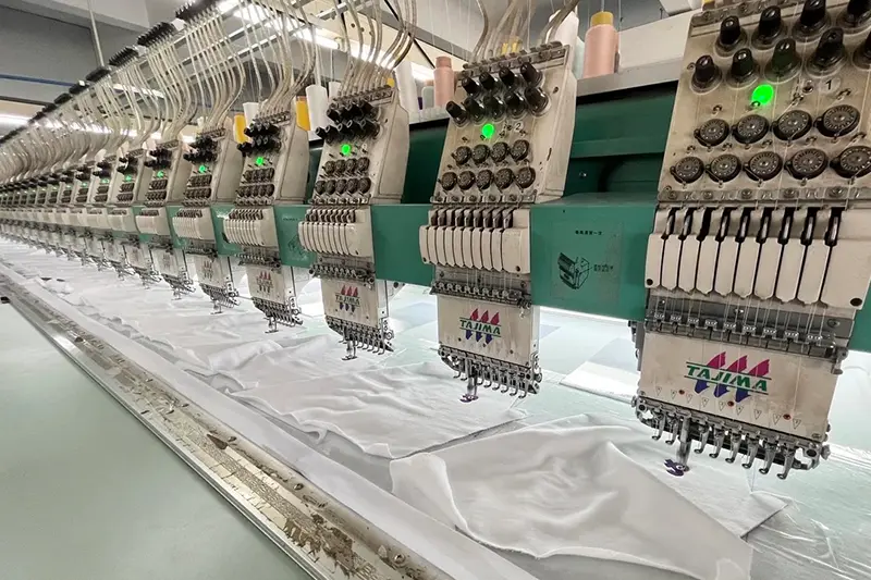 Multi-head embroidery machines stitching designs onto white fabric.