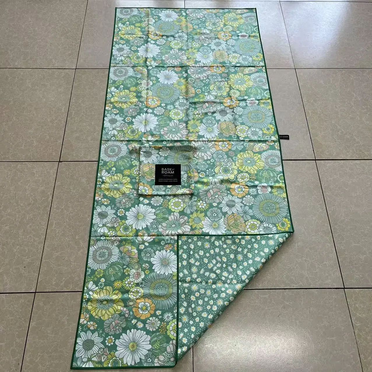 Floral beach towel with a folded corner showing a small daisy-pattern reverse and a matching floral pouch.