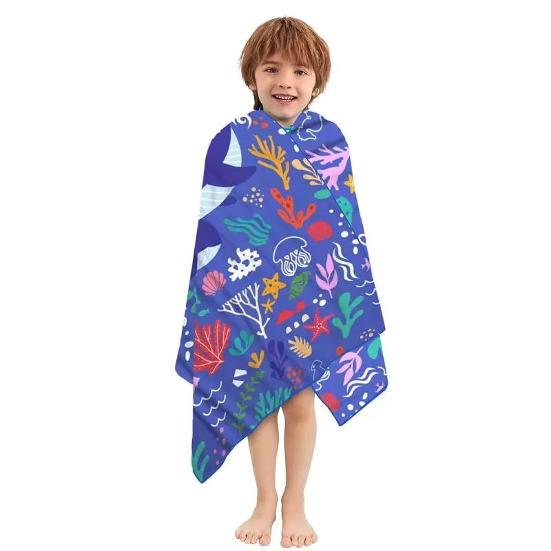 Child wrapped in a blue beach towel with colorful ocean-life prints.