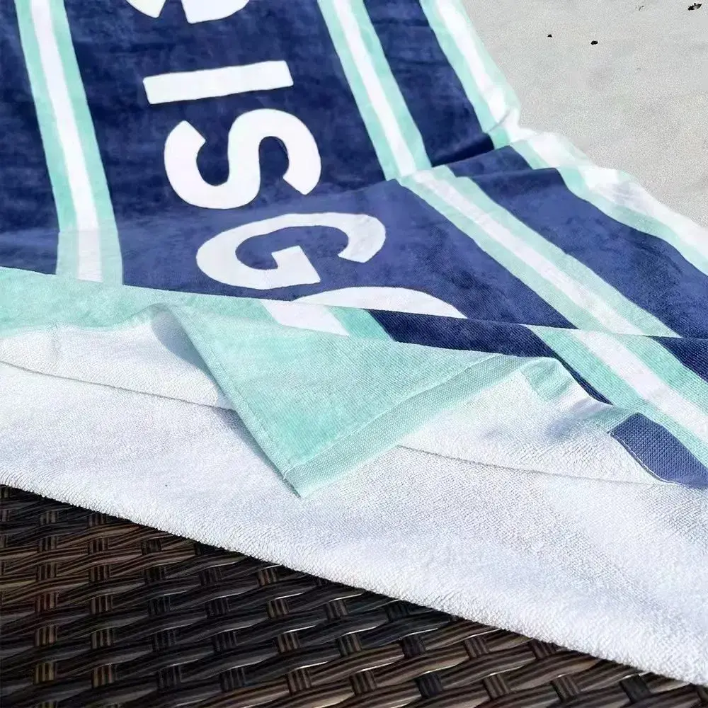Folded corner of a navy and mint striped towel showing its white reverse and stitched edge.