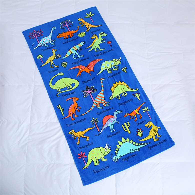 Blue beach towel with colorful dinosaur illustrations laid flat on a white background.